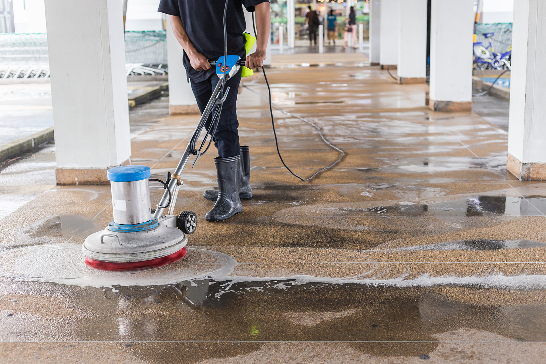 Worker cleaning sand wash exterior walkway using polishing machi