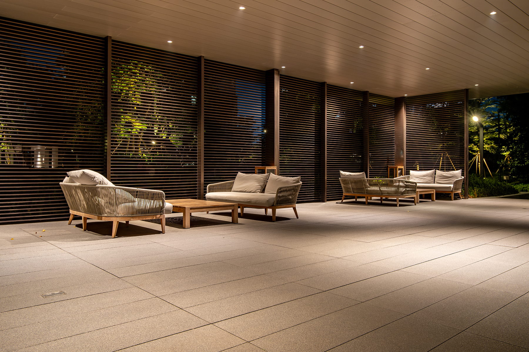 A modern, open-air lounge at night within a residential apartmen